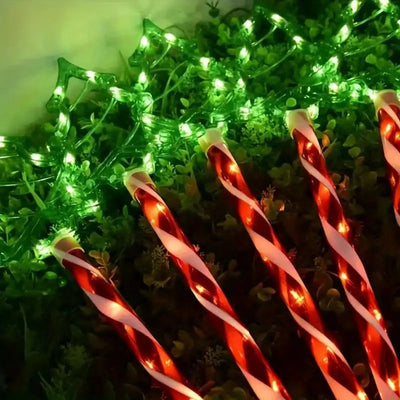 Piquets solaires sucre d'orge éclairant un jardin de Noël