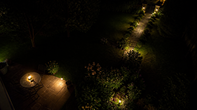 Vue d'ensemble d'un jardin la nuit avec plusieurs zones d'éclairage solaire d'intensités différentes