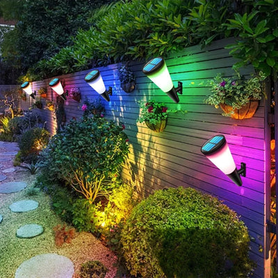 Appliques solaires multicolores le long d'un mur de jardin la nuit