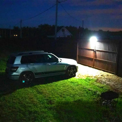 Applique solaire 1000lm éclairant un jardin avec voiture la nuit