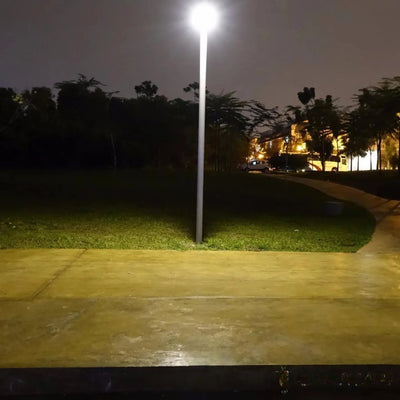 Lampadaire solaire éclairant une allée de parc la nuit