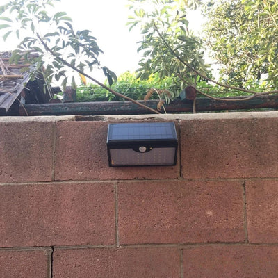 Lampe solaire 1300lm installée sur un mur en briques